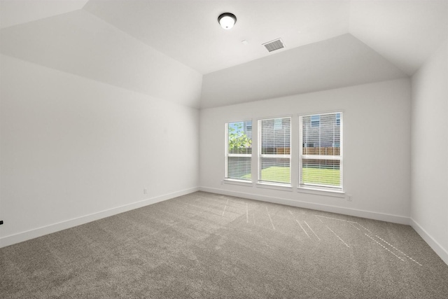 unfurnished room with vaulted ceiling, visible vents, carpet flooring, and baseboards