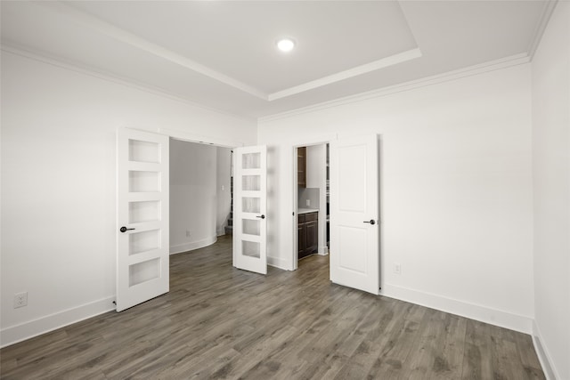 unfurnished bedroom featuring dark wood-type flooring, crown molding, and a tray ceiling