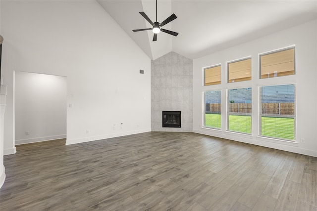 unfurnished living room with wood-type flooring, ceiling fan, high vaulted ceiling, and a tile fireplace