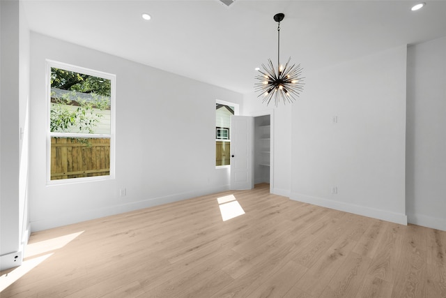 empty room with a notable chandelier and light hardwood / wood-style flooring