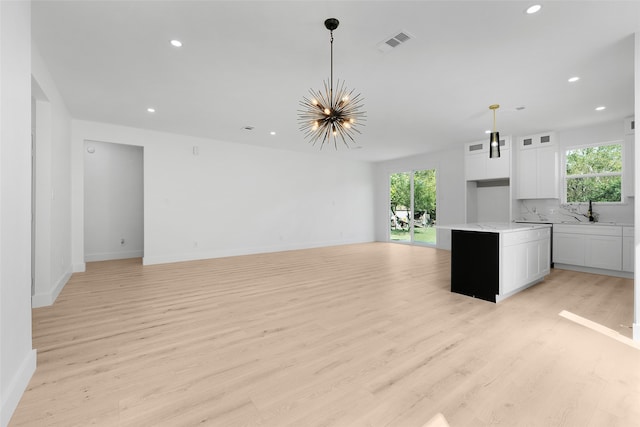 unfurnished living room with plenty of natural light, light hardwood / wood-style floors, and a chandelier