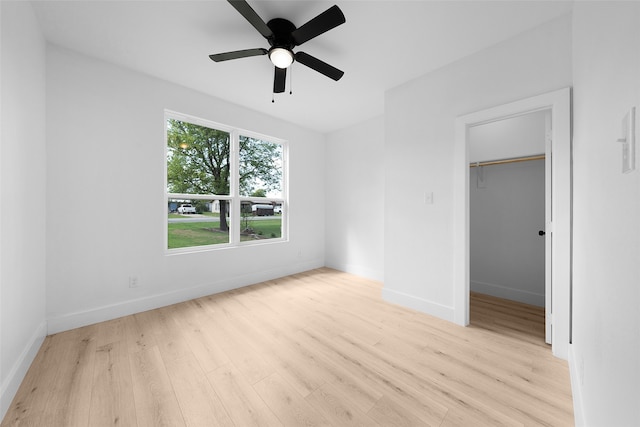 unfurnished bedroom featuring ceiling fan, light hardwood / wood-style flooring, a closet, and a walk in closet