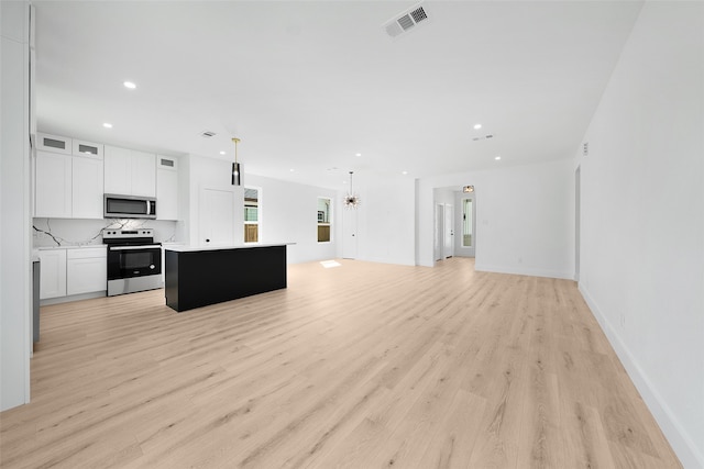 kitchen featuring white cabinets, hanging light fixtures, appliances with stainless steel finishes, a center island, and light hardwood / wood-style floors