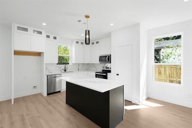 kitchen featuring white cabinets, stainless steel appliances, hanging light fixtures, and a center island