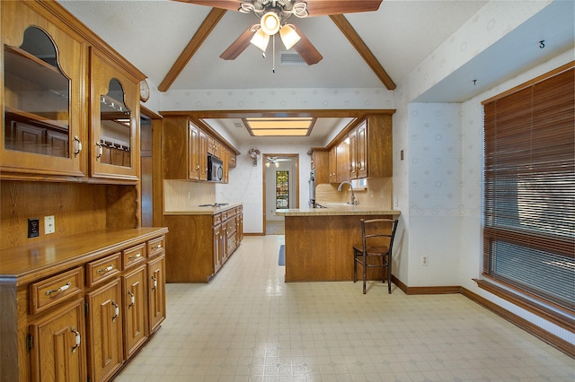 kitchen with sink, kitchen peninsula, ceiling fan, white gas cooktop, and a breakfast bar area