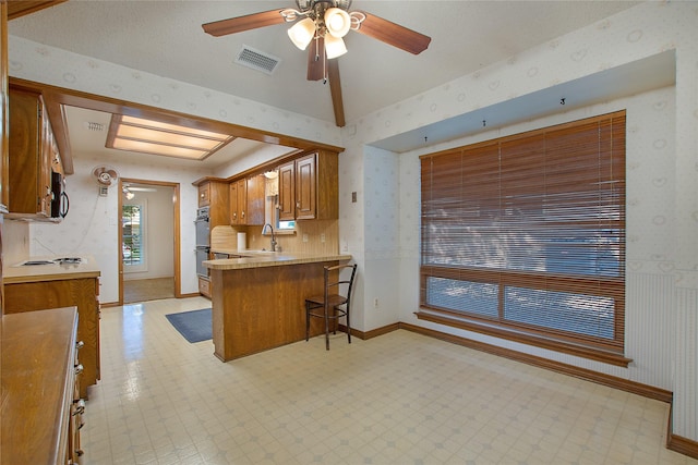 kitchen featuring light floors, a sink, a kitchen bar, and wallpapered walls