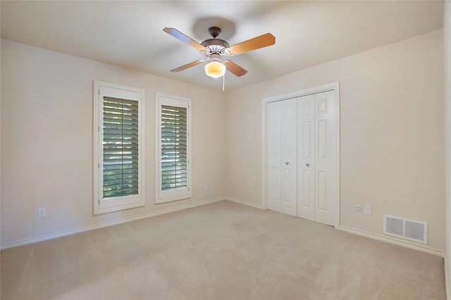 unfurnished bedroom featuring light colored carpet, a closet, visible vents, and baseboards