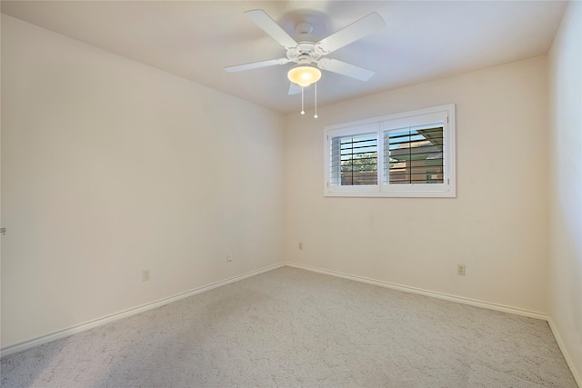 carpeted spare room featuring a ceiling fan and baseboards