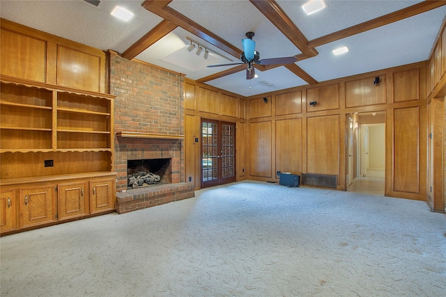 unfurnished living room featuring a brick fireplace, beam ceiling, and light colored carpet