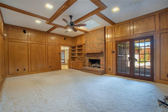 unfurnished living room featuring built in shelves, a decorative wall, carpet flooring, wood walls, and beamed ceiling