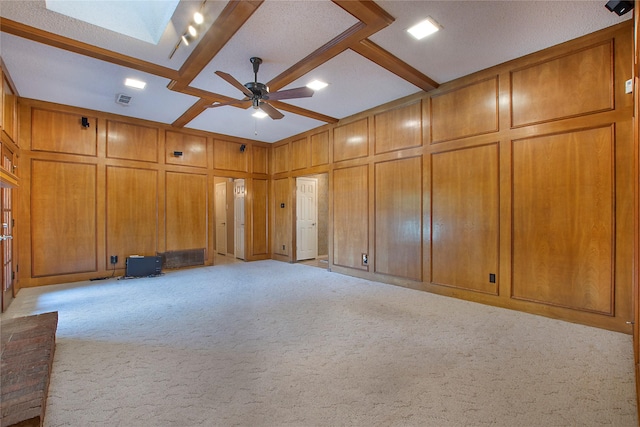 spare room with ceiling fan, a decorative wall, light colored carpet, visible vents, and beamed ceiling