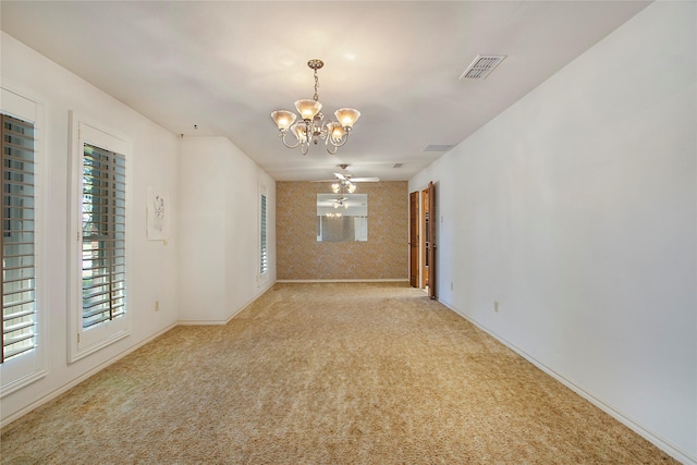 carpeted spare room with ceiling fan with notable chandelier, visible vents, and baseboards