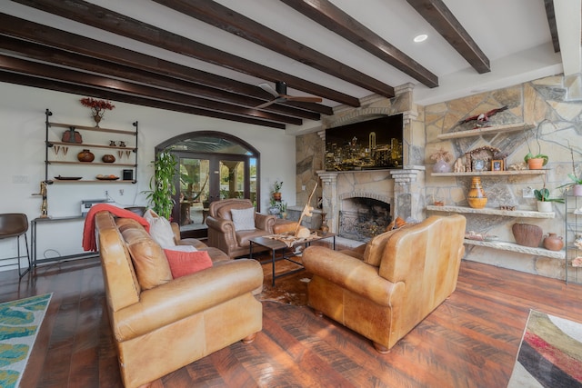 living room featuring dark hardwood / wood-style floors, a fireplace, ceiling fan, and beamed ceiling