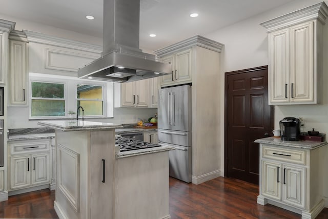 kitchen with island exhaust hood, stainless steel fridge, a center island, and light stone countertops