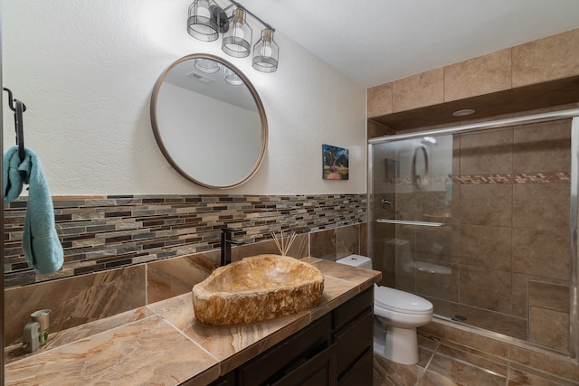 bathroom featuring decorative backsplash, a shower with door, vanity, and toilet