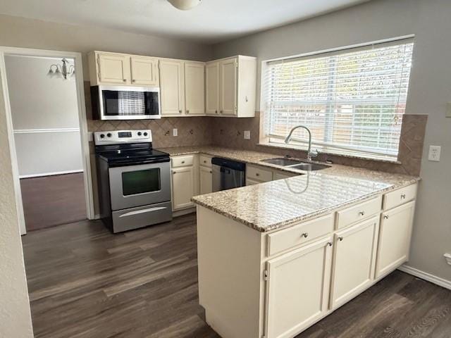 kitchen with appliances with stainless steel finishes, dark hardwood / wood-style flooring, tasteful backsplash, light stone counters, and sink