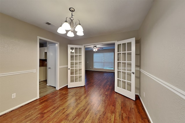 unfurnished dining area with hardwood / wood-style floors, ceiling fan with notable chandelier, and french doors