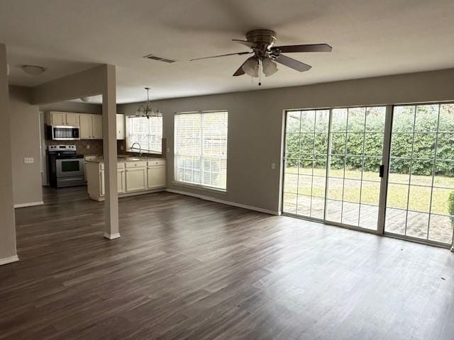 unfurnished living room featuring ceiling fan with notable chandelier, dark hardwood / wood-style flooring, and sink