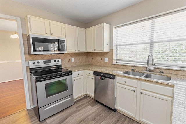 kitchen featuring backsplash, light wood-style floors, stainless steel appliances, and a sink