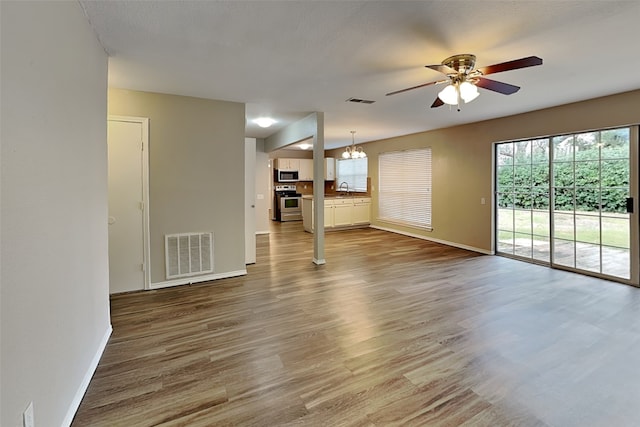 unfurnished living room with hardwood / wood-style floors, ceiling fan with notable chandelier, and sink