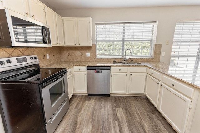 kitchen with decorative backsplash, wood finished floors, stainless steel appliances, and a sink
