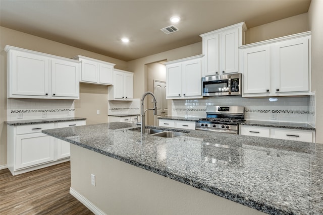 kitchen with white cabinets, appliances with stainless steel finishes, dark hardwood / wood-style floors, and sink