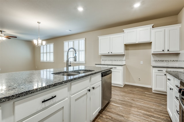 kitchen with dark stone counters, stainless steel appliances, white cabinets, and sink