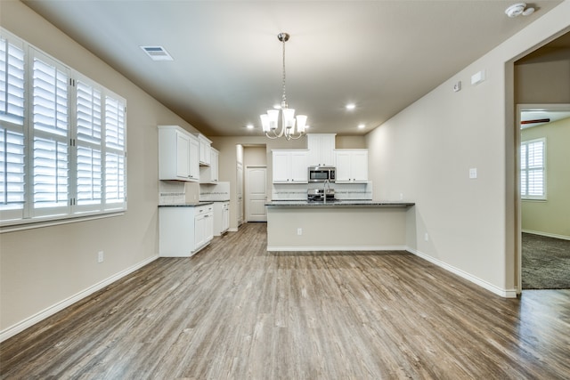 kitchen with decorative light fixtures, appliances with stainless steel finishes, light wood-type flooring, and white cabinetry