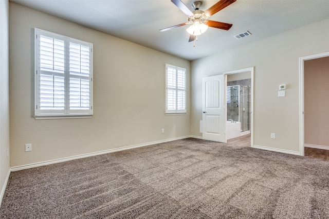 unfurnished bedroom with ensuite bath, carpet, multiple windows, and ceiling fan