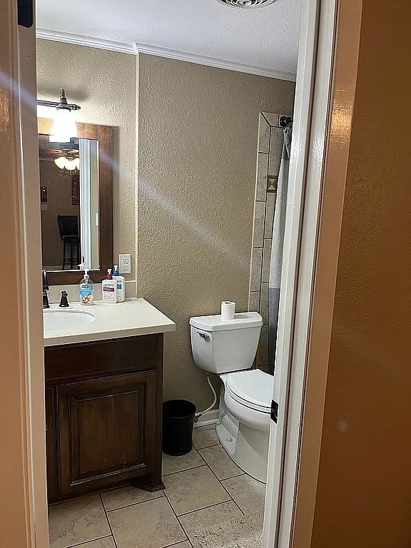 bathroom with vanity, toilet, a shower with curtain, crown molding, and tile patterned flooring