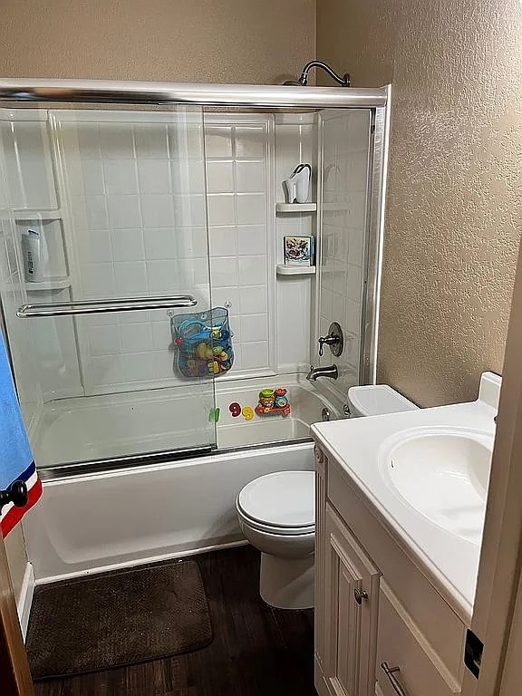 full bathroom with enclosed tub / shower combo, hardwood / wood-style floors, vanity, and toilet