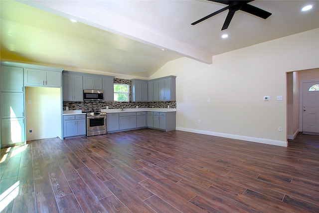 kitchen with dark wood-type flooring, gray cabinets, stainless steel appliances, ceiling fan, and vaulted ceiling with beams