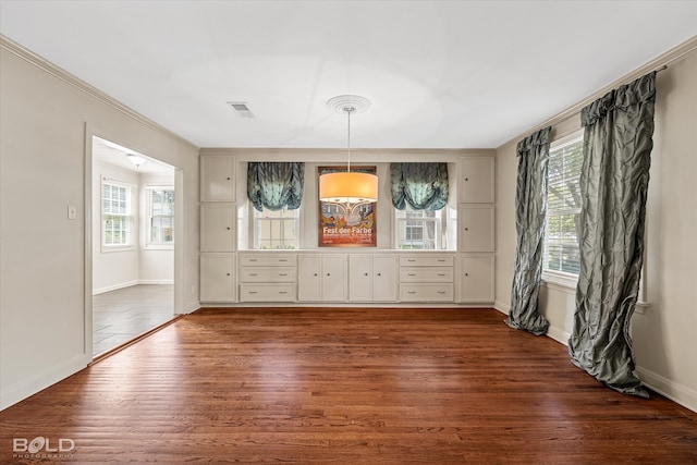 interior space featuring plenty of natural light, dark wood-type flooring, and crown molding