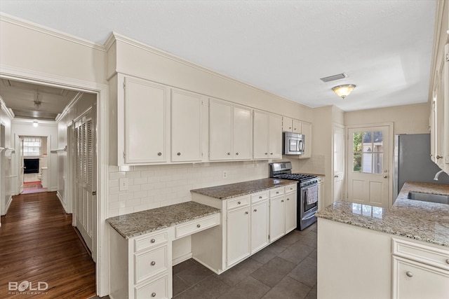 kitchen with stainless steel appliances, dark wood-type flooring, light stone counters, decorative backsplash, and white cabinetry