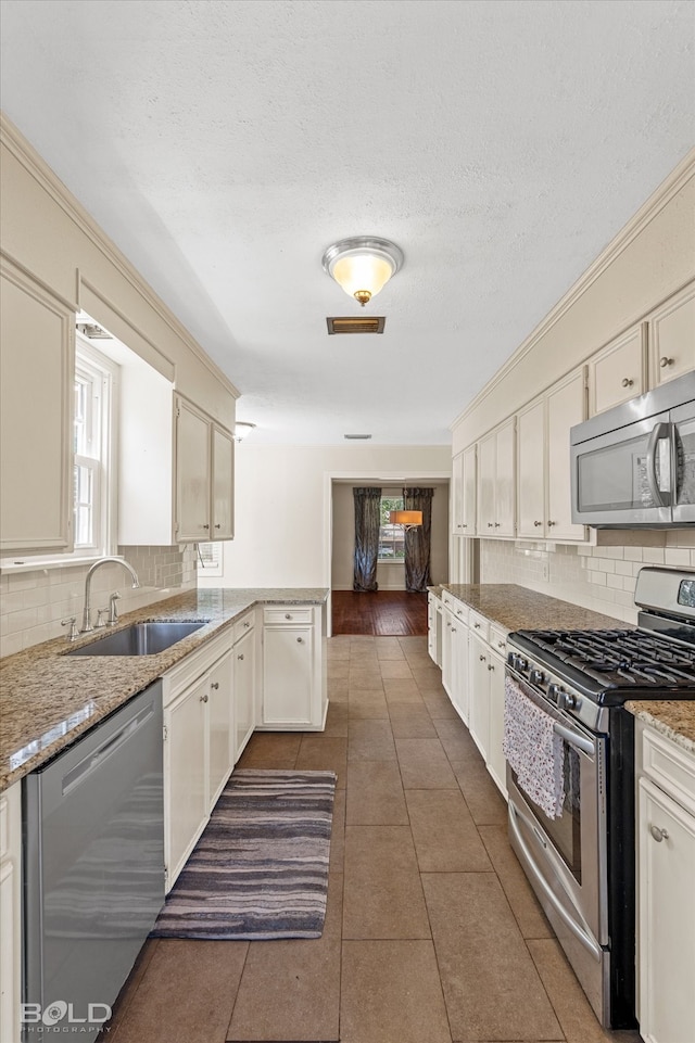 kitchen featuring dark tile patterned flooring, stainless steel appliances, sink, and backsplash