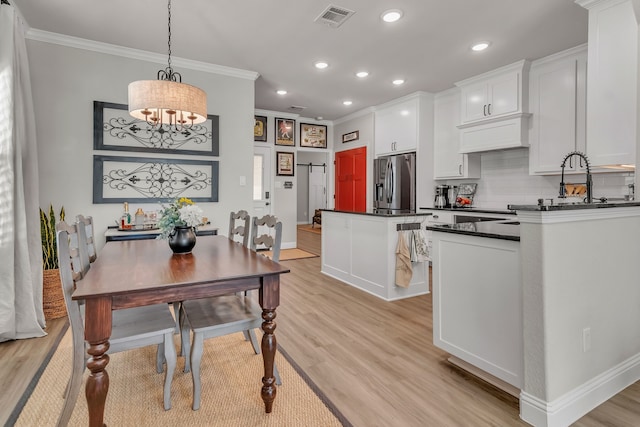 kitchen with white cabinetry, a barn door, light hardwood / wood-style flooring, pendant lighting, and stainless steel refrigerator with ice dispenser