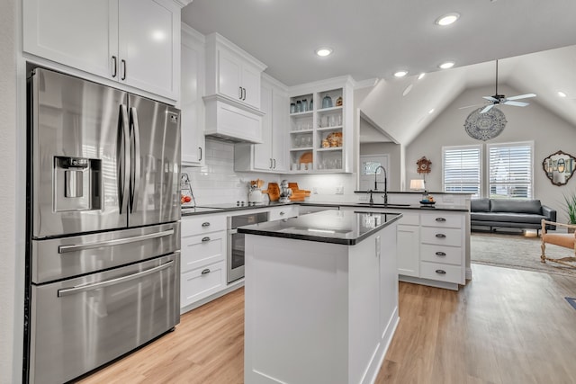 kitchen with kitchen peninsula, white cabinets, light hardwood / wood-style flooring, stainless steel refrigerator with ice dispenser, and sink