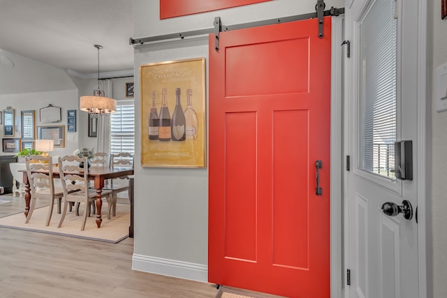 entrance foyer featuring light hardwood / wood-style flooring, a notable chandelier, and a barn door