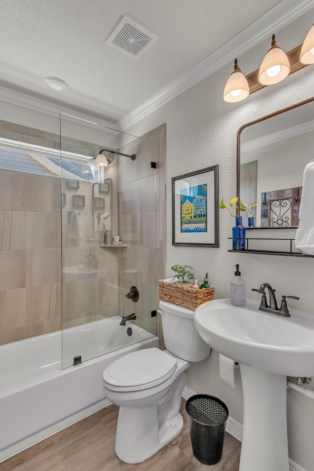 bathroom featuring toilet, crown molding, wood-type flooring, and tiled shower / bath