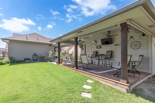 rear view of property with a wooden deck, a yard, and ceiling fan