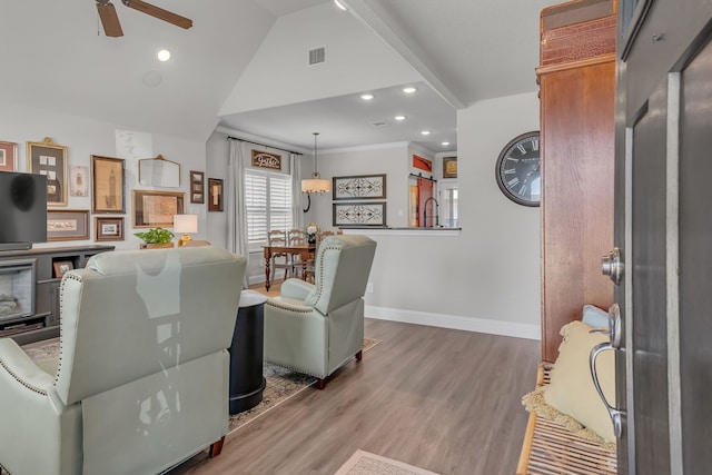 living room with hardwood / wood-style floors, ceiling fan, and vaulted ceiling