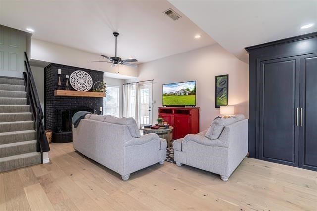 living room featuring a fireplace, ceiling fan, and light hardwood / wood-style flooring