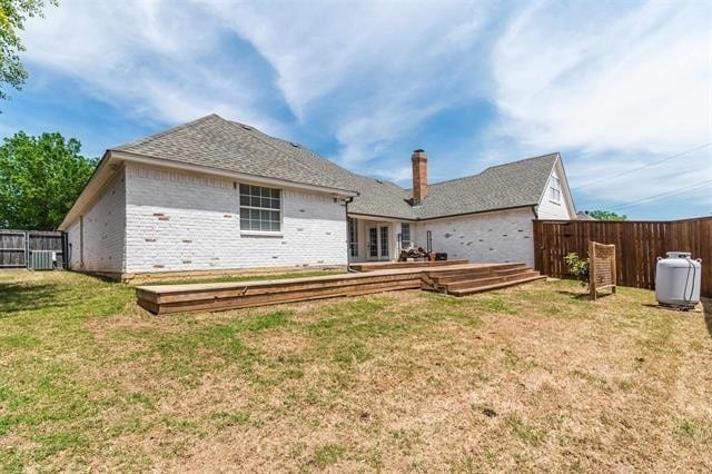 rear view of property featuring a lawn and central AC