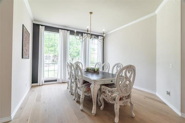 dining area with ornamental molding, an inviting chandelier, and light hardwood / wood-style floors