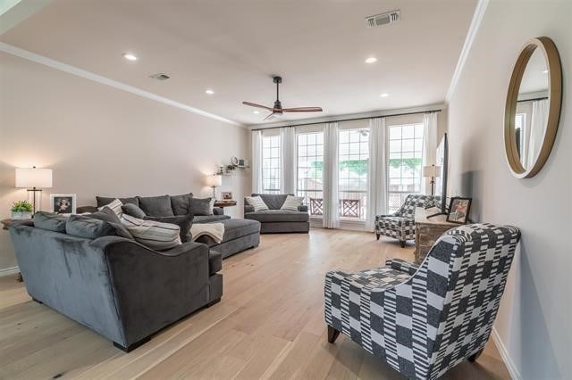 living room featuring ceiling fan, ornamental molding, and light hardwood / wood-style floors