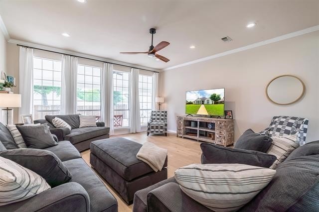 living room featuring light hardwood / wood-style floors, ceiling fan, and crown molding