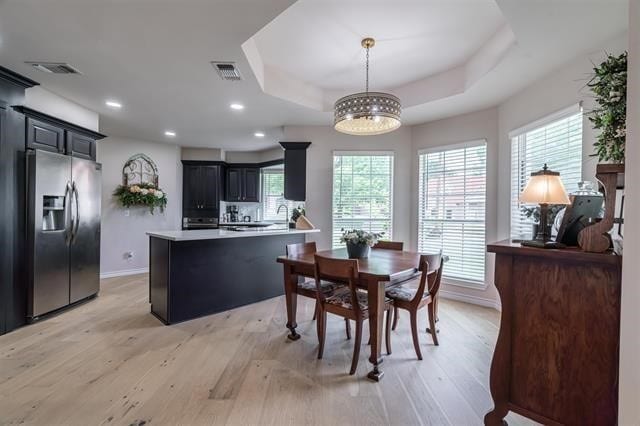 dining room featuring light hardwood / wood-style floors, a tray ceiling, and an inviting chandelier