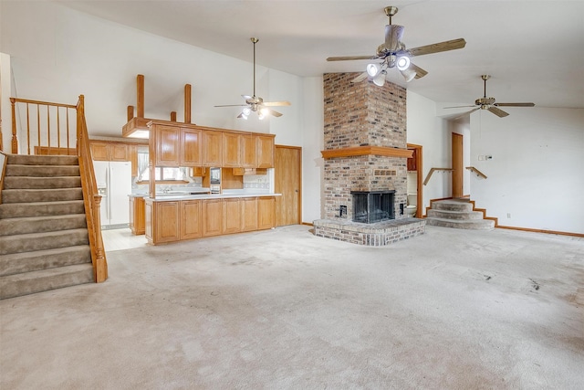 unfurnished living room with a fireplace, ceiling fan, light carpet, and high vaulted ceiling