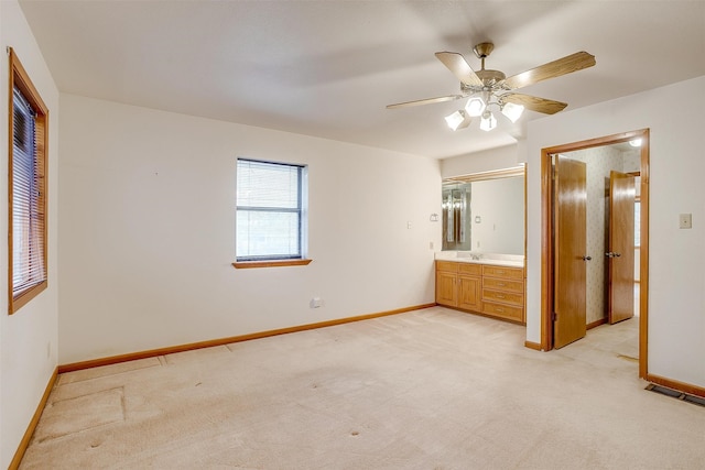 unfurnished bedroom with ensuite bathroom, ceiling fan, light carpet, and a closet