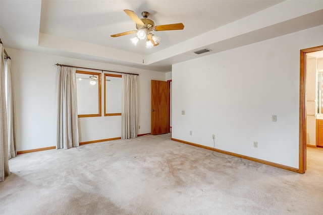 carpeted spare room featuring ceiling fan and a raised ceiling